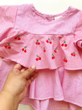 A red and pink striped children's shirt with small embroidered cherries in the middle.