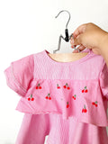 A red and pink striped children's shirt with small embroidered cherries in the middle.